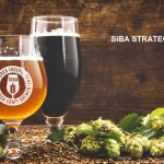 beer surrounded by hops on wooden background